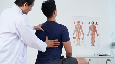 A physiotherapist conducting a postural assessment on a young man.