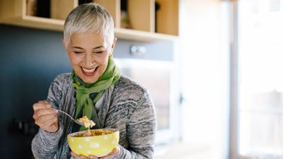 Elderly woman eating food from a bowl