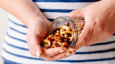 Hands pouring assorted nuts out of a jar
