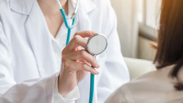 Doctor holding stethoscope to patient