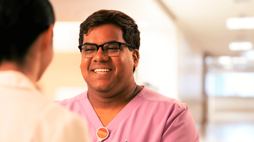 man with glasses wearing an Orlando Health pin smiling at someone